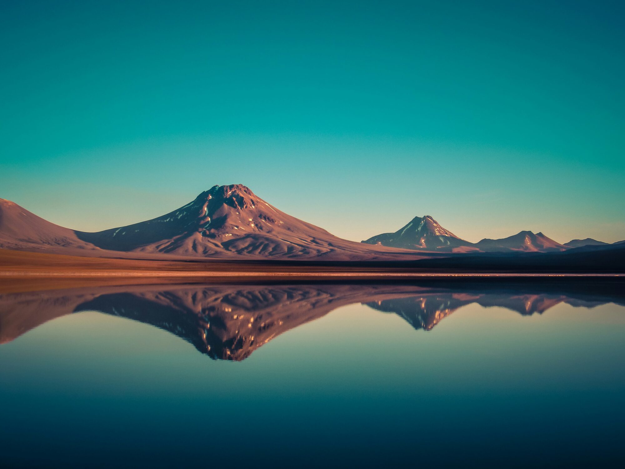 Volcán reflejado en una laguna altiplánica al amanecer